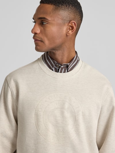 Männermodel draagt Sweatshirt mit Label-Print van Guess, regular fit, katoenmix, geribde boorden, ronde hals, Nahaufnahme bovenlichaam.