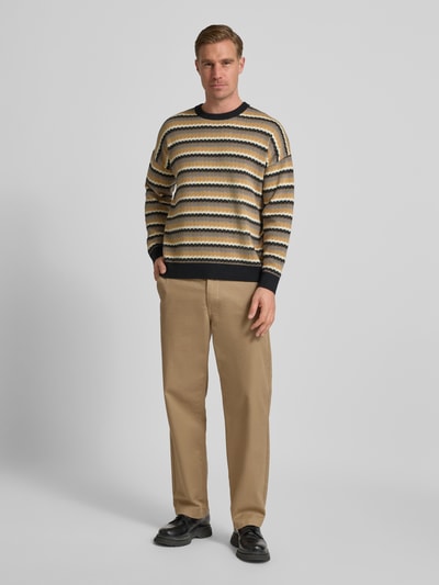 Männermodel trägt Strickpullover mit Rundhalsausschnitt Modell 'Neelio' von Drykorn im Baumwoll-Woll-Mix, Relaxed-Fit, Ganzkörperansicht von vorne.