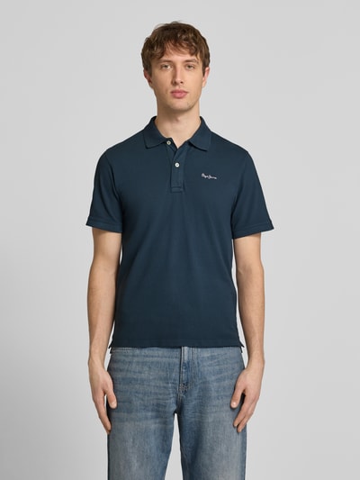 Męski model nosi Regular Fit Poloshirt aus reiner Baumwolle Modell 'OSCAR' von Pepe Jeans, efekt: jednolity kolor, aplikacja: wyhaftowane logo, kołnierzyk polo, dekolt w serek, krótkie zapięcie na guziki, rękaw: krótki rękaw, zakończenie rękawów: prążkowane, wykończenie: z rozcięciami po bokach, wykończenie materiału: pika, materiał: czysta bawełna, widok całej sylwetki od przodu.