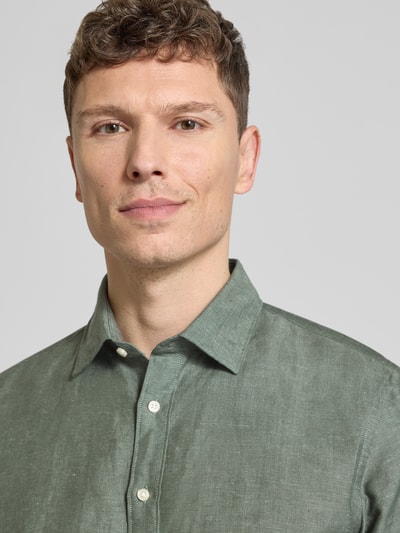 Männermodel trägt Slim Fit Freizeithemd aus Leinen-Mix von Jake*s in Olivgrün mit Kentkragen und Knopfleiste, Nahaufnahme Oberkörper. Baumwollanteil sorgt für angenehme Textur, Kurzarm-Design für lockeren Stil.