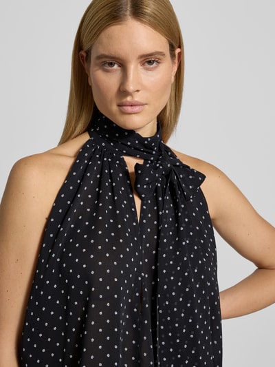 Frauenmodel trägt Bluse mit floralem Allover-Print von ROTATE, semitransparent, Relaxed-Fit, Stehkragen mit Schlüssellochausschnitt, Ärmelloses-Design, Rückenlänge 69 cm bei Größe 36, schwarzer Stoff mit weißem Florales-Allover-Muster, Nahaufnahme Oberkörper.