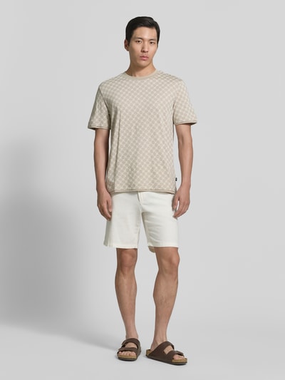 Männermodel trägt T-Shirt mit Logo-Muster und Rundhalsausschnitt von JOOP! Collection aus Baumwoll-Lyocell-Mix, Regular-Fit, Beige auf Weiß, glatte Textur, Rückenlänge bei Größe M: 69 cm, Ganzkörperansicht von vorne.