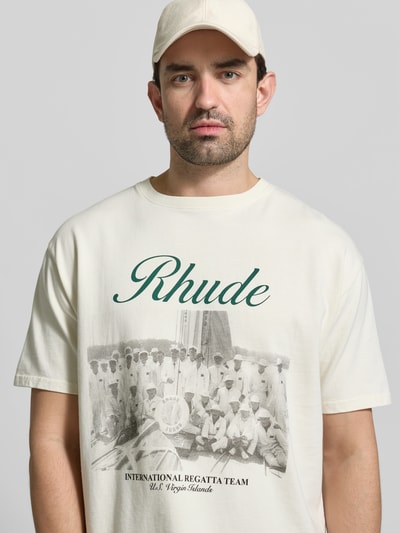 Männermodel trägt Regular Fit T-Shirt aus Baumwolle von RHUDE mit Label-Print und Foto-Print, Rundhalsausschnitt, Nahaufnahme Oberkörper. Herren T-Shirt, Reine Baumwolle, Regular-Fit, Rückenlänge bei Größe M: 72 cm.