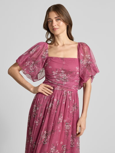 Vrouwenmodel draagt 'Abendkleid mit Karree-Ausschnitt' van LACE & BEADS in chiffon, A-lijn maxijurk, bloemenprint, ballonmouwen, ruches, smokdetail achter, kleuren roze met lichtroze en witte accenten, detailopname bovenlichaam.