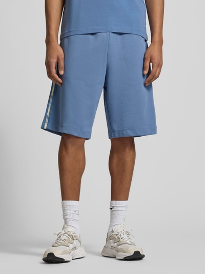 Männermodel trägt Sweatshorts mit Label-Details und Eingrifftaschen von EA7 Emporio Armani, Relaxed-Fit, Baumwoll-Mix, Ganzkörperansicht von vorne.