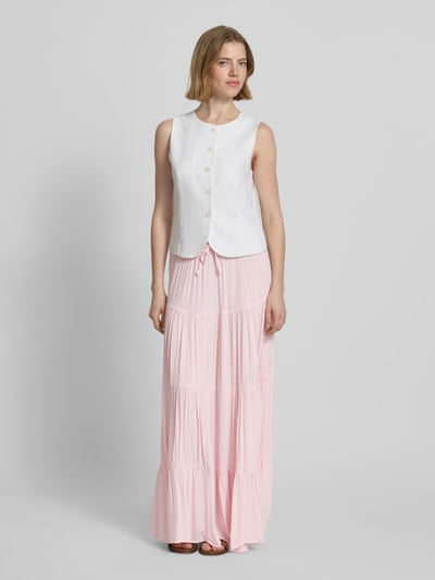 Frauenmodel trägt Maxirock im Stufen-Look von REVIEW aus reiner Viskose in zartem Rosa, A-Linie, Tunnelzug, Ganzkörperansicht von vorne.