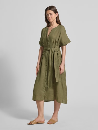 Frauenmodel trägt olivgrünes Midikleid aus reinem Leinen mit Tunika-Ausschnitt, Modell 'Soli' von Christian Berg Woman Selection, taillierte Passform, kurzärmelig, durchgehende Knopfleiste, Stoffband, Ganzkörperansicht von vorne