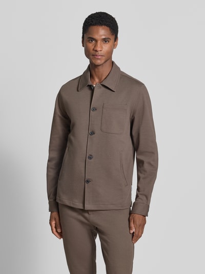 Männermodel trägt Slim Fit Hemdjacke mit Viskose-Anteil von Lindbergh in Braun, Umlegekragen, Knopfleiste, Brusttasche, Ganzkörperansicht von vorne.