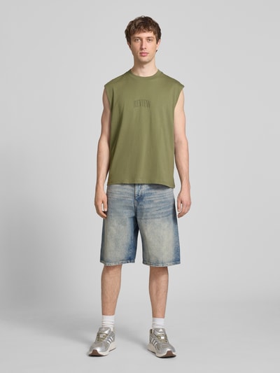 Männermodel trägt Muskelshirt mit Logo und Rundhalsausschnitt von REVIEW in Grün, Reine Baumwolle, Regular-Fit, Logo, Rückenlänge bei Größe M: 68 cm, Ganzkörperansicht von vorne.