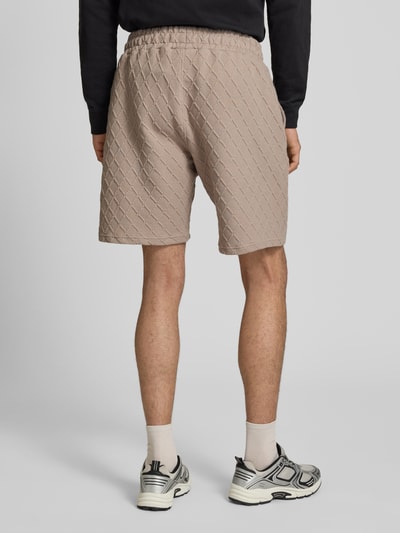 Männermodel trägt Relaxed Fit Shorts mit Strukturmuster Modell 'Jovren' von Pegador, Elastischer-Material-Mix, Herren, Ganzkörperansicht Rückansicht.
