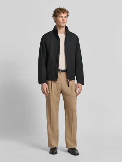 Męski model nosi czarną kurtkę pikowaną ze stójką Regular Fit Steppjacke mit Stehkragen Modell 'LIGHT' od Strellson, zdjęcie całej sylwetki z przodu, kurtka kontekst Herren Steppjacke von Strellson.