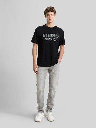 Männermodel trägt Relaxed Fit T-Shirt aus reiner Baumwolle von Tom Tailor Denim, Optik: Unifarben, Label-Print, Rundhals, Kurzarm, Ganzkörperansicht von vorne.