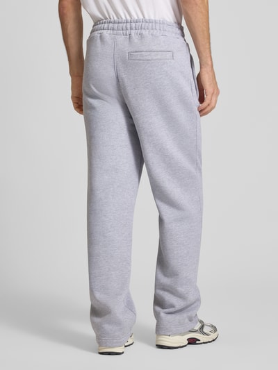 Männermodel trägt Loose Fit Sweatpants aus Baumwoll-Mix mit Label-Detail von PEGADOR, grauer Farbton, elastischer Bund, Eingrifftaschen, Ganzkörperansicht Rückansicht.