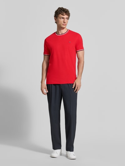 Męski model nosi T-Shirt mit Kontraststreifen und Rundhalsausschnitt od Christian Berg Men, bawełna z domieszką elastanu, krój regular fit, kontrastowe paski, okrągły dekolt, długość tyłu w rozmiarze M: 71 cm, widok całej sylwetki z przodu.