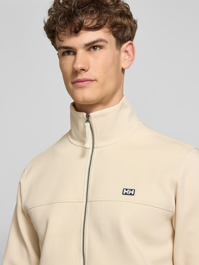 Männermodel trägt Sweatjacke mit Label-Patch Modell 'KOSTER' von Helly Hansen in Beige, Baumwoll-Mix, Reißverschluss, Nahaufnahme Oberkörper.