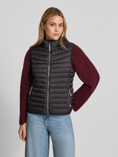 Vrouwenmodel draagt 'Weste in Stepp-Optik' van FUCHS SCHMITT, zwarte bodywarmer met stiksels, getailleerd, opstaande kraag, tweewegritssluiting, ruglengte maat 36: 55 cm, schouderbreedte: 39 cm, borstwijdte: 48 cm, kleuren zwart en bordeaux, gladde textuur, volledige vooraanzicht.