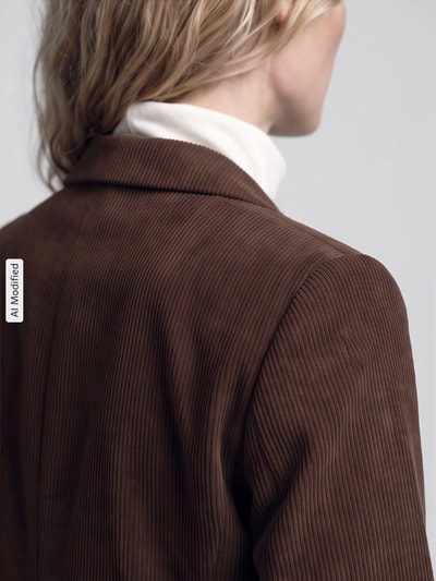 Frauenmodel trägt taillierten Kurzblazer mit 3/4-Arm Modell 'BOSELLA' von PIECES in Braun, feine Rippstruktur, Nahaufnahme Rückansicht, KI-modifiziertes Bild.