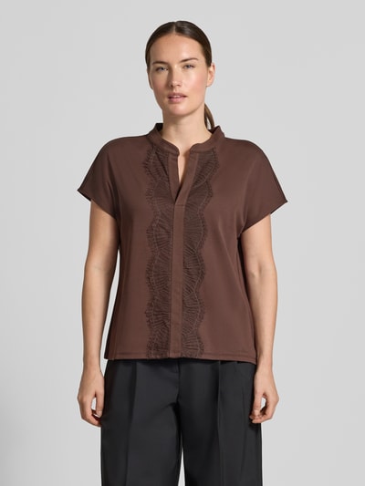 Frauenmodel trägt Regular Fit Bluse aus Baumwoll-Mix mit Spitzenbesatz von Marc Cain, braun, Serafino-Ausschnitt, Kurzarm, Ganzkörperansicht von vorne.