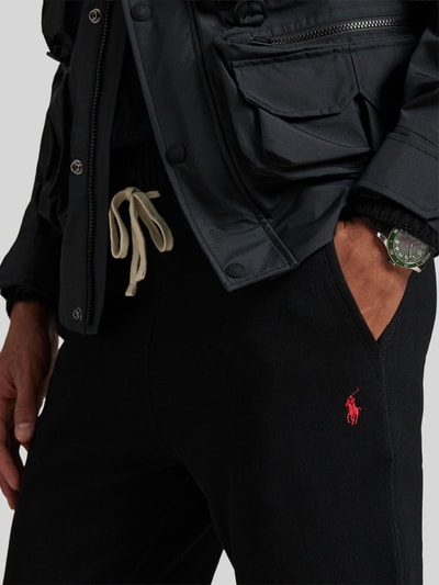 Męski model nosi Regular Fit Sweatshorts aus Baumwoll-Mix von Polo Ralph Lauren, kolor jednolity, logo, bawełniany materiał sweat, krój regular fit, elastyczny pas i nogawki, boczne kieszenie, detal z przodu, zbliżenie na górną część.