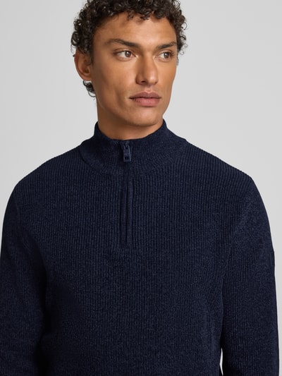 Männermodel trägt Regular Fit Troyer aus Baumwoll-Mix von Tom Tailor in Unifarben Strickoptik, Reißverschluss, Label-Patch, Nahaufnahme Oberkörper.