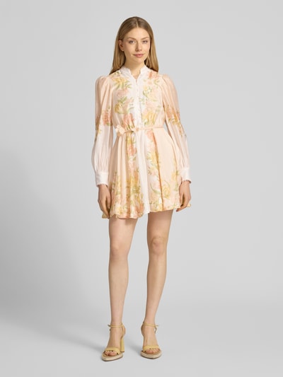 Frauenmodel trägt Cocktailkleid mit Bindegürtel Modell 'Shannah' von Forever New aus Reine Baumwolle, A-Linie, Minikleid, Stehkragen, Knopfleiste, florales Muster in Pastelltönen, Ganzkörperansicht von vorne.