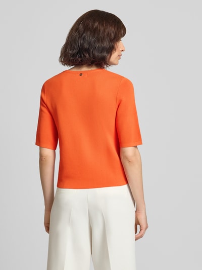 Frauenmodel trägt Strickpullover aus Viskose-Mix mit 1/2-Arm von Rich & Royal in Orange, glatte Textur, Regular Fit, Ganzkörperansicht Rückansicht.