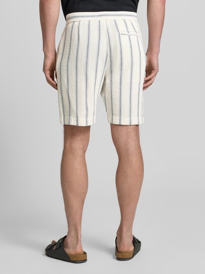 Männermodel trägt Regular Fit Shorts aus reiner Baumwolle Modell 'REGCAL' von SELECTED HOMME, cremefarben mit blauen Streifen, Strukturstoff, Ganzkörperansicht Rückansicht.