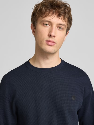 Männermodel trägt Longsleeve aus Baumwolle Modell 'FILLIP' von Blend in Dunkelblau, Strukturmuster, Nahaufnahme Oberkörper, Reine Baumwolle, Gerader-Schnitt, Rundhalsausschnitt, Label-Detail, Rückenlänge bei Größe M 70 cm.