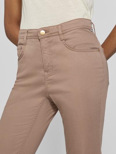 Frauenmodel trägt Regular Fit Gerade Hose aus Lyocell-Mix mit Modal-Baumwoll-Anteil Modell 'MARY' von Brax, beigefarbene glatte Oberfläche, Nahaufnahme Oberkörper, Damen Gerade Hose von Brax.