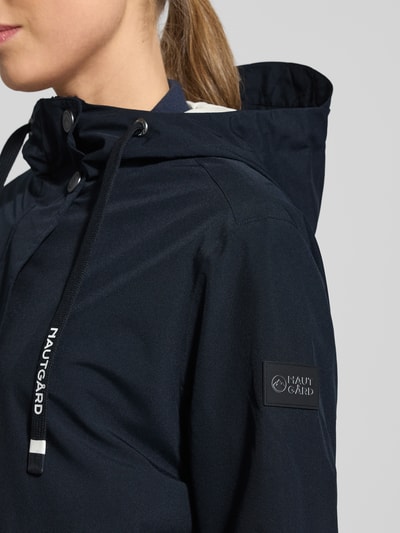 Kobiece modelka nosi kurtka z kapturem 'Jacke mit Ärmelriegeln' od NAUTGÅRD, kolor granatowy, patki przy mankietach, detal, zbliżenie na górę.