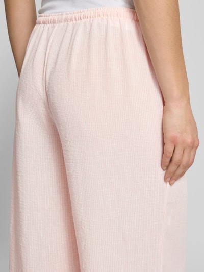 Frauenmodel trägt Pyjama Pants mit elastischem Bund von Review, Damen Loose-Fit mit Kordelzug, zartrosa mit feiner Struktur, Detailaufnahme Rückansicht. Bundweite bei Größe S: 41 cm, Innenbeinlänge bei Größe S: 77 cm.