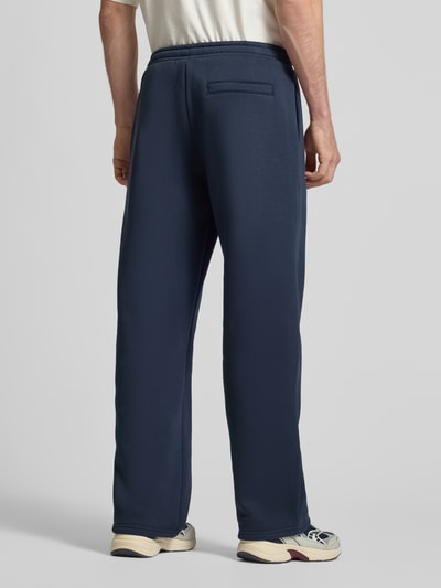 Männermodel trägt Sweatpants aus Baumwoll-Mix von REVIEW in Dunkelblau mit geradem Schnitt, elastischem Bund, Ganzkörperansicht Rückansicht.