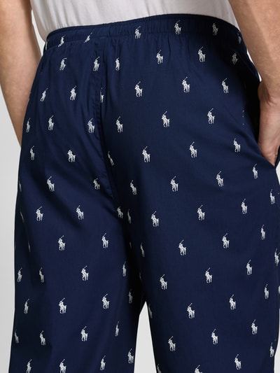 Mężczyznę w spodniach Comfort Fit Pyjama-Hose aus reiner Baumwolle Modell 'PJ PANT-SLEEP-BOTTOM' od Polo Ralph Lauren Underwear, wzór w białe logo polo pony, ciemnoniebieski kolor, miękka bawełniana faktura, boczne kieszenie, elastyczny pas, widok z tyłu, zbliżenie na dolną część pleców.