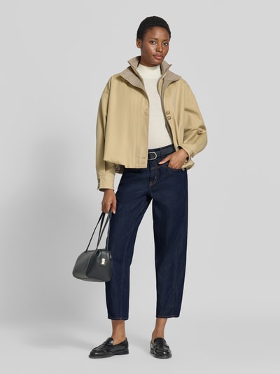 Frauenmodel trägt Straight Fit Jeans mit Knopfverschluss von COMMA aus Baumwoll-Lyocell-Mix in Dunkelblau, kombiniert mit heller Jacke, ganzkörperansicht von vorne. Bundweite und Innenbeinlänge gemäß Größe 36, sichtbare seitliche Eingrifftaschen und Gesäßtaschen.