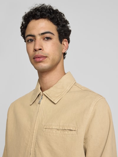 Mannelijk model draagt Jacke mit Zweiwege-Reißverschluss van Jack & Jones in beige, puur katoen, regular fit, platte kraag, Nahaufnahme bovenlichaam. Ruglengte maat M 65 cm, schouderbreedte 48 cm, borstwijdte 59 cm, mouwlengte 66 cm.