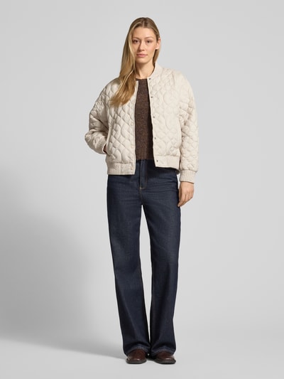 Kobiece modelka nosi Jacke mit Stehkragen und Eingrifftaschen von Fuchs Schmitt, krój regular fit, pikowanie, stójka, listwa guzikowa, wpuszczane kieszenie, długość tyłu w rozmiarze 36: 58 cm, szerokość ramion w rozmiarze 36: 48 cm, szerokość klatki piersiowej w rozmiarze 36: 57 cm, długość rękawów w rozmiarze 36: 56 cm, jasny beż, ciemnoniebieskie spodnie, gładkie tekstury, całkowity widok z przodu