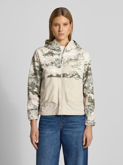 Kobieta modelka nosi Regular Fit kurtkę z kapturem model 'Spired Valley' od Columbia w beżowe i zielone wzory, nakładane kieszenie, długość tyłu w rozmiarze S: 59 cm, szerokość ramion w rozmiarze S: 42 cm, szerokość klatki piersiowej w rozmiarze S: 55 cm, długość rękawów w rozmiarze S: 60 cm, widok całej sylwetki z przodu.