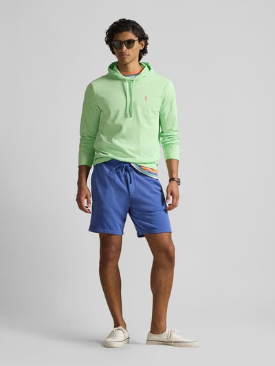 Männermodel trägt Regular Fit Sweatshorts aus Baumwoll-Mix von Polo Ralph Lauren in Blau, unifarben, Logo-Stitching, seitliche Eingrifftaschen, Ganzkörperansicht von vorne.