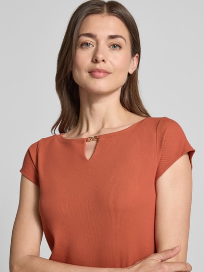 Modelka kobieca nosi T-Shirt mit Cut Out od Marc Cain z modalem i stretch, prosty krój, drobny prążek, okrągły dekolt, kolor ceglasty, zbliżenie na górną część ciała.