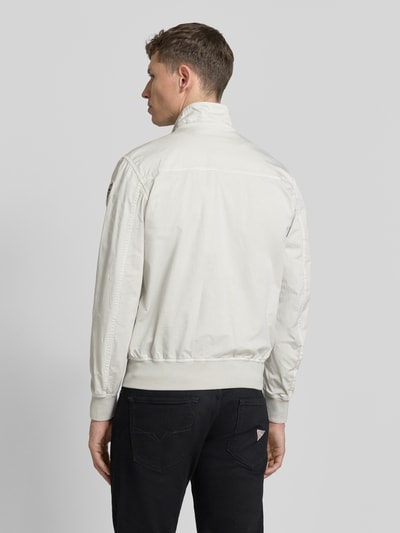 Männermodel trägt Jacke mit Zweiwege-Reißverschluss Modell 'Badger' von Blauer Usa aus Baumwoll-Elasthan-Mix, Regular-Fit, Stehkragen, Pattentaschen, Rückenlänge bei Größe M 64 cm, Schulterbreite 40 cm, Brustweite 50 cm, Ärmellänge 63 cm, helle Farbe, glatte Textur, Ganzkörperansicht Rückansicht.