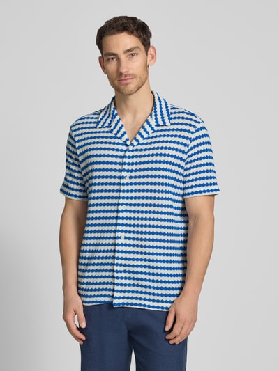 Męski model nosi Relaxed Fit Poloshirt aus Baumwoll-Mix Modell 'DYLAN' von SELECTED HOMME, efekt: wzór na całej powierzchni, kołnierz z połami, dekolt w serek, zapięcie: listwa guzikowa, rękaw: krótki rękaw, drobny splot, mieszanka bawełny, Ganzkörperansicht von vorne.