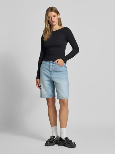 Frauenmodel trägt schwarzes Slim Fit Shirt aus Baumwoll-Mix Modell 'MAYA' von NOISY MAY®, Ripp-Optik, U-Boot-Ausschnitt, Ganzkörperansicht von vorne.