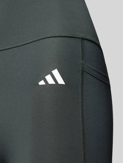 Produktfoto, Eng anliegende Sport-Leggings mit Gesäßtasche von adidas Training in dunklem Grauton, glatte Textur, Nahaufnahme