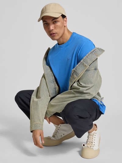 Männermodel trägt Relaxed Fit T-Shirt mit Logo-Stitching von Forét in Blau, Reine Baumwolle, Rundhalsausschnitt, Kurzärmelig, Ganzkörperansicht von vorne