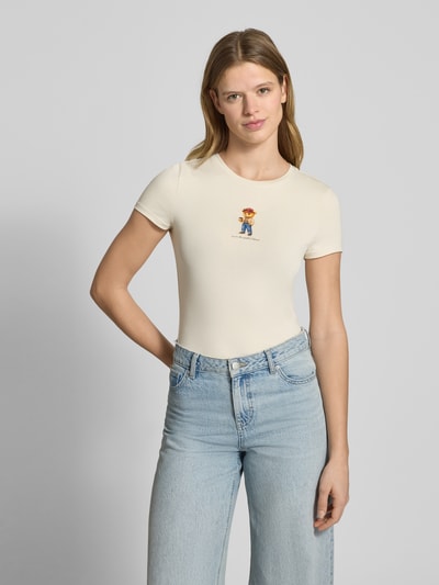 Kobiece modelka nosi damski t-shirt od REVIEW Slim Fit T-Shirt mit Logo-Print Modell 'Sweet', elastyczna mieszanka bawełny, krój slim fit, nadruk z logo, okrągły dekolt, długość tyłu w rozmiarze S: 52 cm, jasny kolor, gładka tekstura, widok całej sylwetki z przodu.