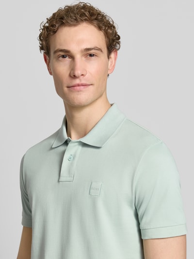 Männermodel trägt Regular Fit Poloshirt aus Baumwoll-Mix Modell 'PASSENGER' von BOSS Orange in Optik: Unifarben, Nahaufnahme Oberkörper.