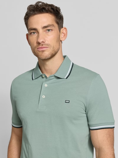 Männermodel trägt Regular Fit Poloshirt mit Kontraststreifen von Christian Berg Men aus Reine Baumwolle mit Knopfleiste, Nahaufnahme Oberkörper.