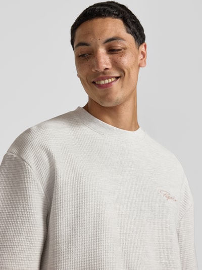 Männermodel trägt Oversized T-Shirt mit Strukturmuster und Label-Stitching von Pegador aus reiner Baumwolle, Nahaufnahme Oberkörper.