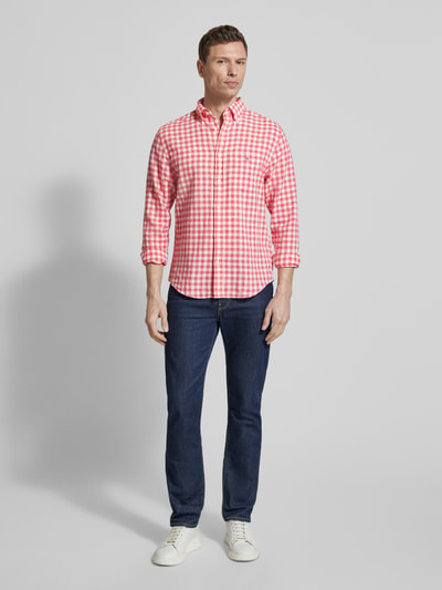 Männermodel trägt Regular Fit Leinenhemd mit Baumwoll-Anteil Modell 'GINGHAM' von Gant in Rot-Weiß Karo, Hemd mit Brusttasche, Ganzkörperansicht von vorne.