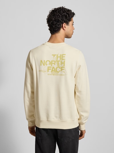 Männermodel trägt Sweatshirt mit Label-Print von The North Face in Creme, Reine Baumwolle, Regular-Fit, Gerippte Abschlüsse, Rundhalsausschnitt, Rückenlänge 69 cm, Ärmellänge 72 cm, Ganzkörperansicht Rückansicht.